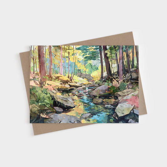 Watercolor-style greeting card featuring a peaceful forest scene with tall trees, dappled sunlight, and a rocky stream flowing through the woods. The card rests on a kraft paper envelope against a white background.