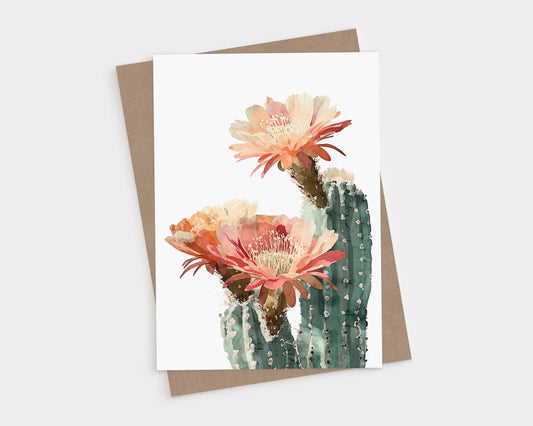 Watercolor greeting card featuring a tall green cactus with three large blooming flowers in warm shades of coral, peach, and cream, shown against a white background with a kraft paper envelope behind it.