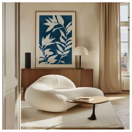Framed cyanotype botanical print featuring curved branches with pointed leaves in white against a deep blue background, displayed in a modern, neutral-toned living room.