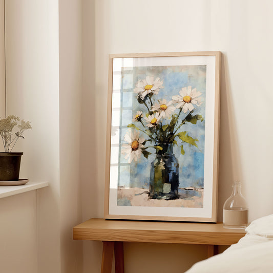 Interior setting with a large framed watercolor painting of white daisies in a blue vase, displayed on a wooden console table next to a small vase and dried flowers.
