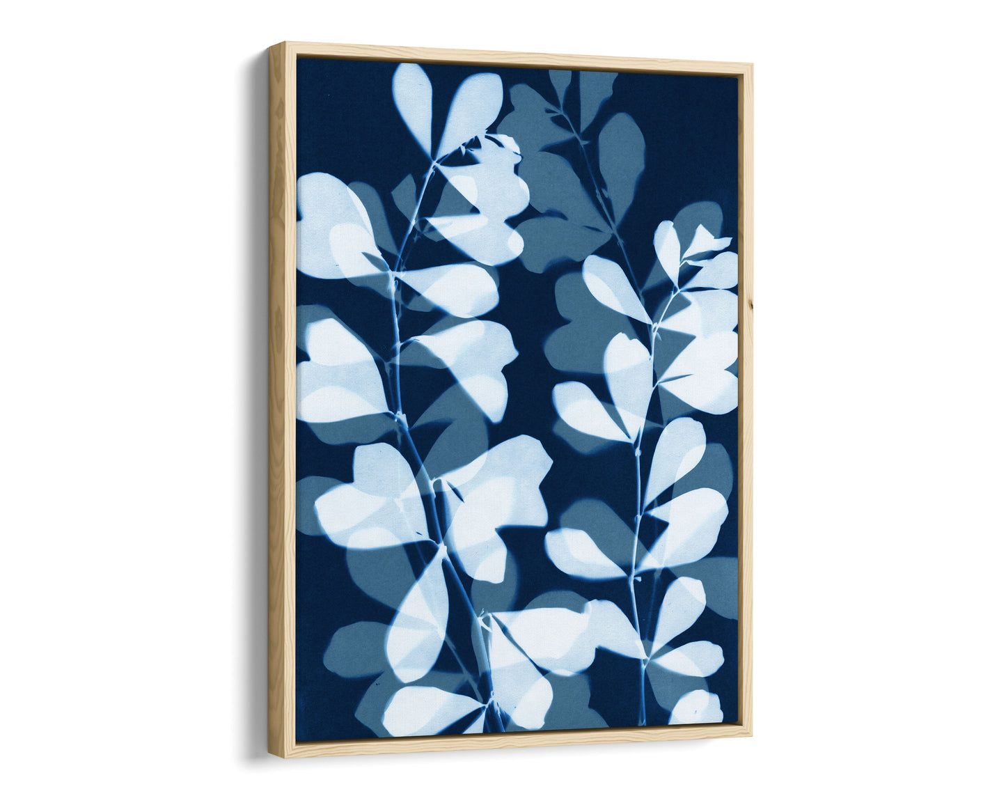 Natural wood framed canvas print featuring overlapping cyanotype-style botanical leaves in soft blue and white against a deep navy background, creating a layered, translucent effect.