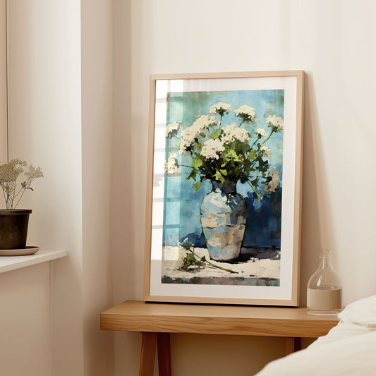 Interior setting with a large framed watercolor painting of white Queen Anne's Lace flowers in a blue striped vase, displayed on a wooden console table next to a small vase and dried flowers.
