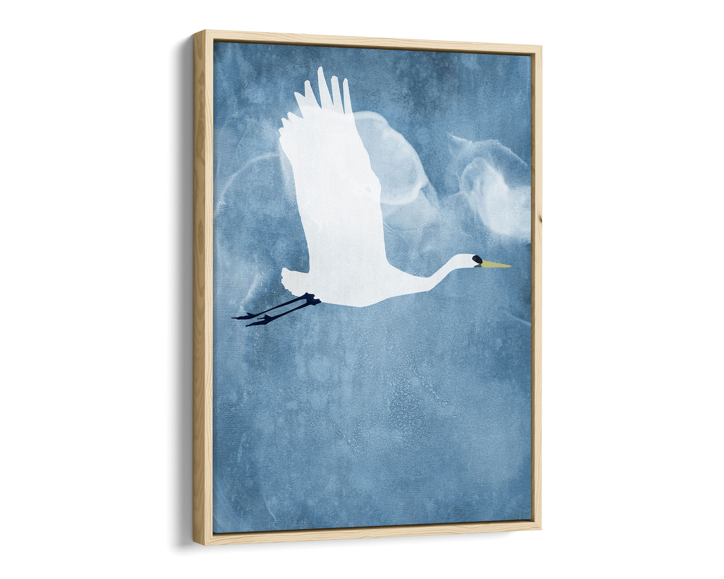 Natural wood framed canvas print of a white heron in mid-flight with wings raised, soaring against a textured blue sky with faint, cloud-like swirls.