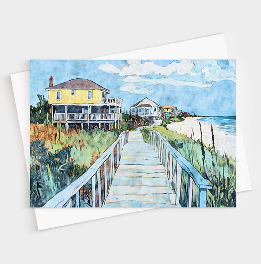 Folded greeting card featuring a vibrant watercolor-style illustration of a coastal boardwalk leading past colorful beach houses toward the ocean. A bright yellow house stands out in the foreground, framed by sea oats, greenery, and soft blue skies, capturing the relaxed charm of a seaside neighborhood.