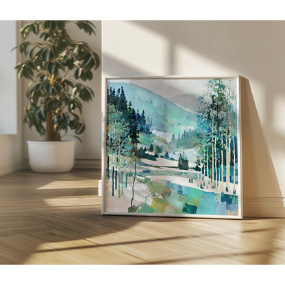 Framed painting of a winter mountain landscape with birch trees, evergreens, and rolling hills in cool shades of blue, teal, and green. The artwork leans against a wall on a wooden floor, bathed in natural sunlight with soft shadows. A potted plant with broad leaves sits nearby, adding a warm, organic touch to the modern interior setting.