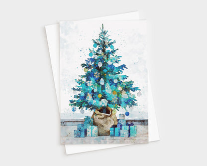 Watercolor-style Christmas card featuring a blue and teal decorated tree in a burlap-wrapped pot, surrounded by matching blue and turquoise presents on a light background, paired with a white envelope.