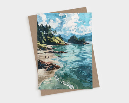 Watercolor-style greeting card featuring a scenic coastal landscape with turquoise waves, sandy beach, rocky shoreline, and pine-covered cliffs under a sky filled with fluffy white clouds. Card is paired with a brown kraft envelope.