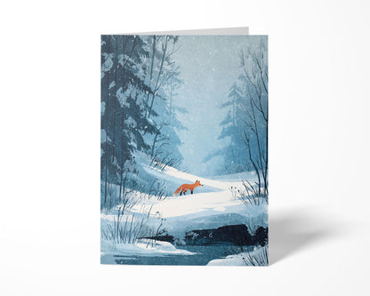 Greeting card featuring a digital painting of a red fox walking through a snowy forest. The scene shows the fox crossing a snow-covered slope above a dark stream, surrounded by bare trees and tall evergreens in soft blue tones, with light snowfall creating a calm, wintry atmosphere.