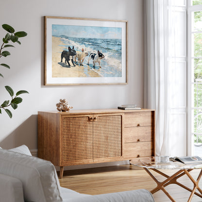 Framed watercolor art of three French Bulldogs walking on a beach displayed in a styled interior with blue and tan coastal tones.