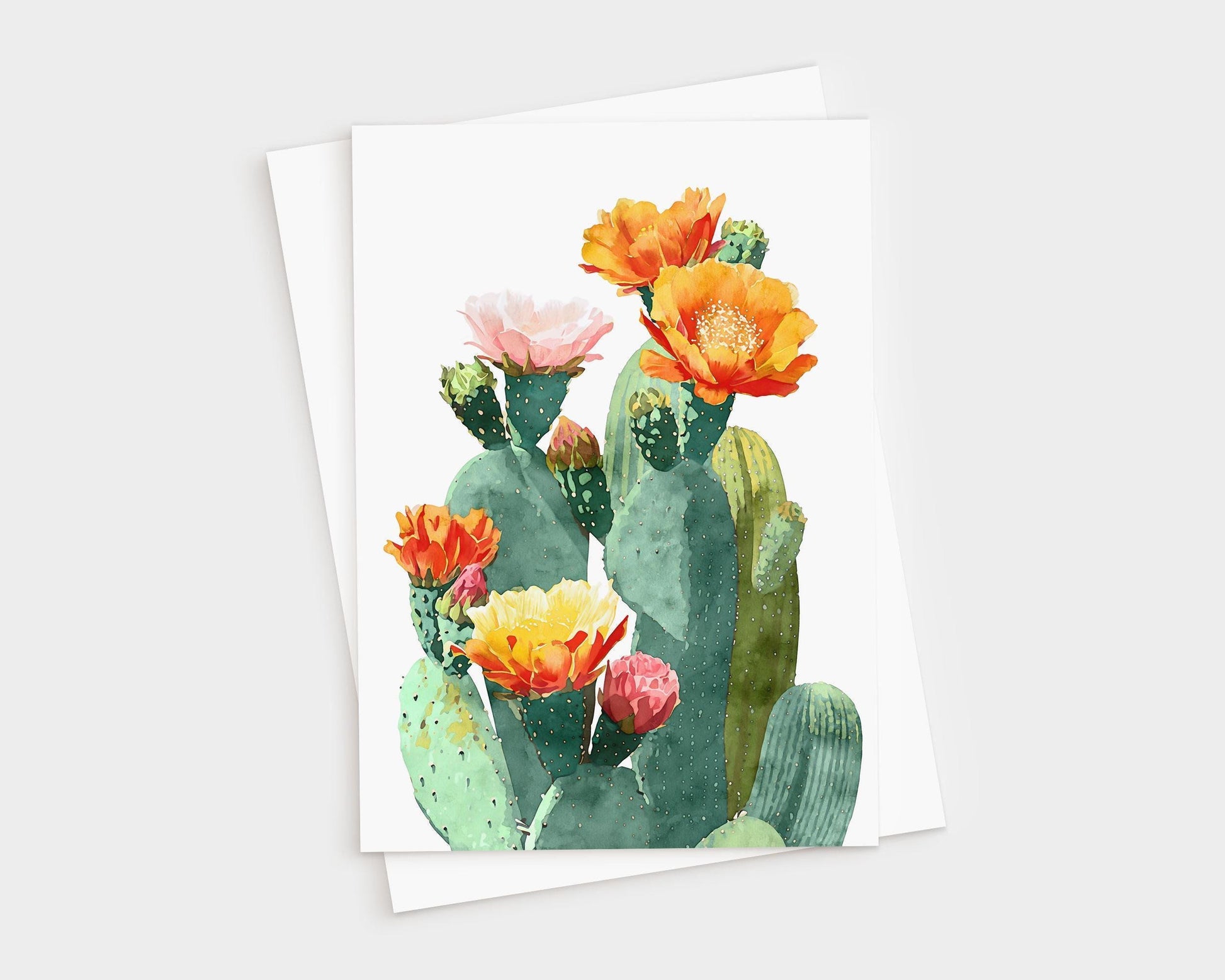 Watercolor greeting card featuring a cluster of green prickly pear cacti with vibrant blossoms in shades of orange, yellow, pink, and red, set against a white background with a white envelope behind it.
