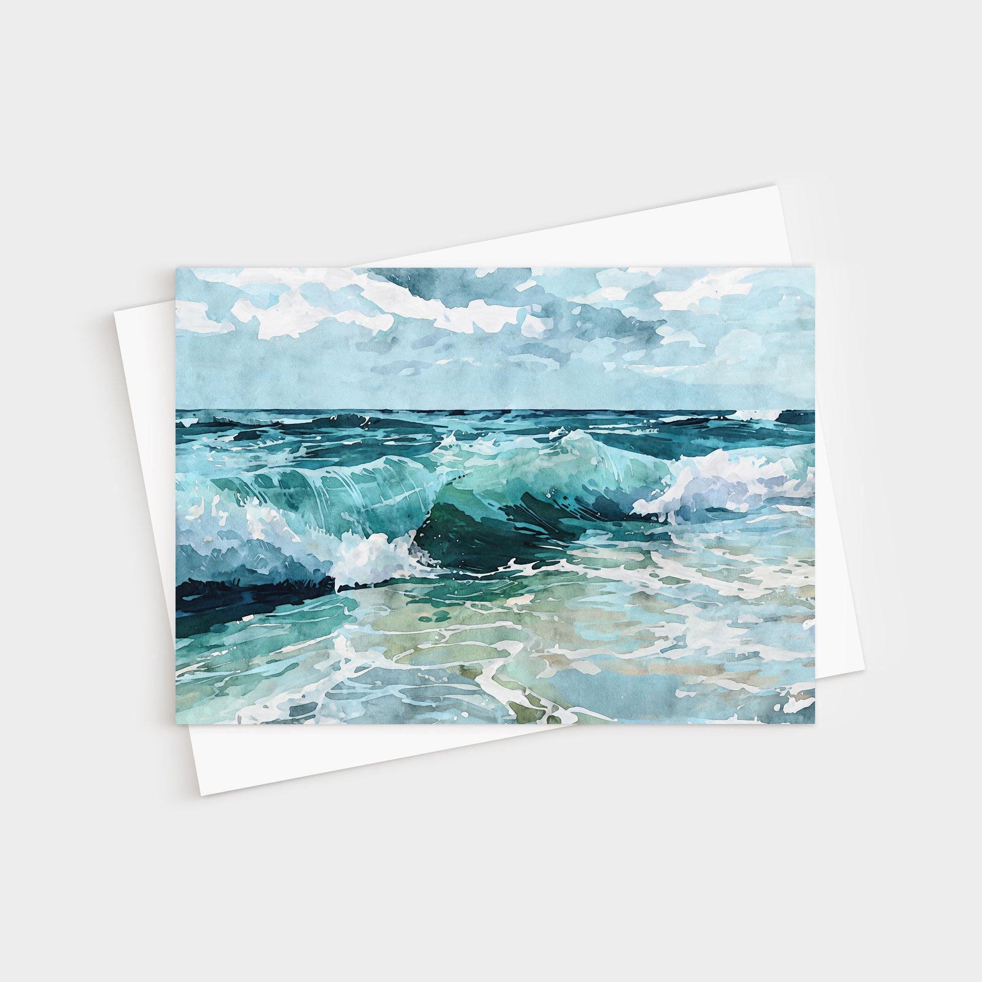 Watercolor greeting card featuring a seascape with turquoise waves crashing onto the shore under a partly cloudy blue sky, paired with a white envelope.