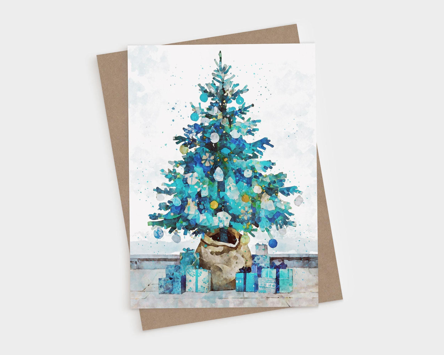 Watercolor-style Christmas card featuring a blue and teal decorated tree in a burlap-wrapped pot, surrounded by matching blue and turquoise presents on a light background, paired with a brown kraft envelope.