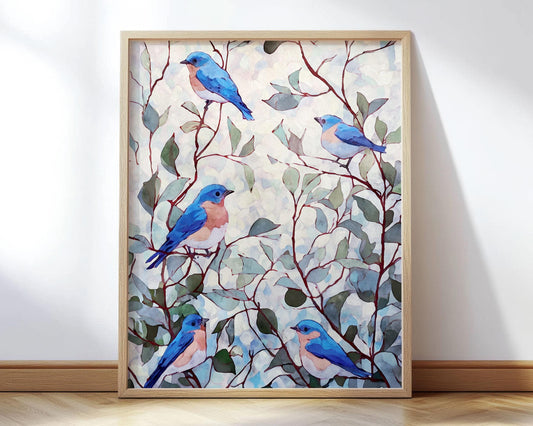Watercolor-style art print featuring five bluebirds perched among slender brown branches with soft green and teal leaves. The background has a light, airy, abstract wash of pale blues and creams. Displayed in a natural wood frame leaning against a white wall on a light wooden floor, the artwork conveys a serene, nature-inspired aesthetic.