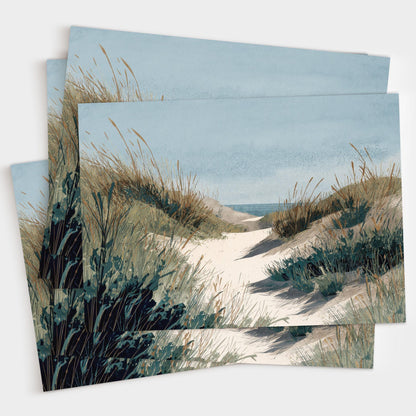 Set of greeting cards featuring a watercolor illustration of a sandy path through grassy dunes leading to the ocean under a calm blue sky, shown stacked in a small pile.