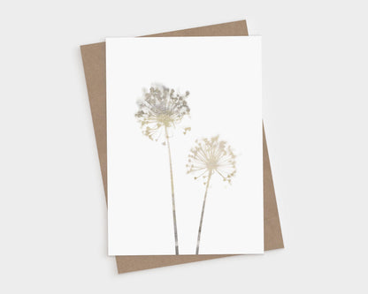 Greeting card featuring two delicate allium flowers in soft beige watercolor tones on white cardstock, paired with a kraft brown envelope, shown on a light background.