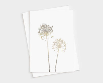 Greeting card featuring two delicate allium flowers in soft beige watercolor tones on white cardstock, paired with a white envelope, shown on a light background.