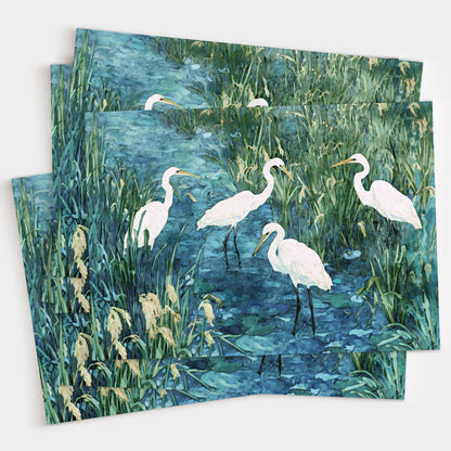 Set of greeting cards featuring a watercolor-style painting of five white egrets standing in a marsh with tall green grasses and deep blue water. Cards are fanned out in a layered display.