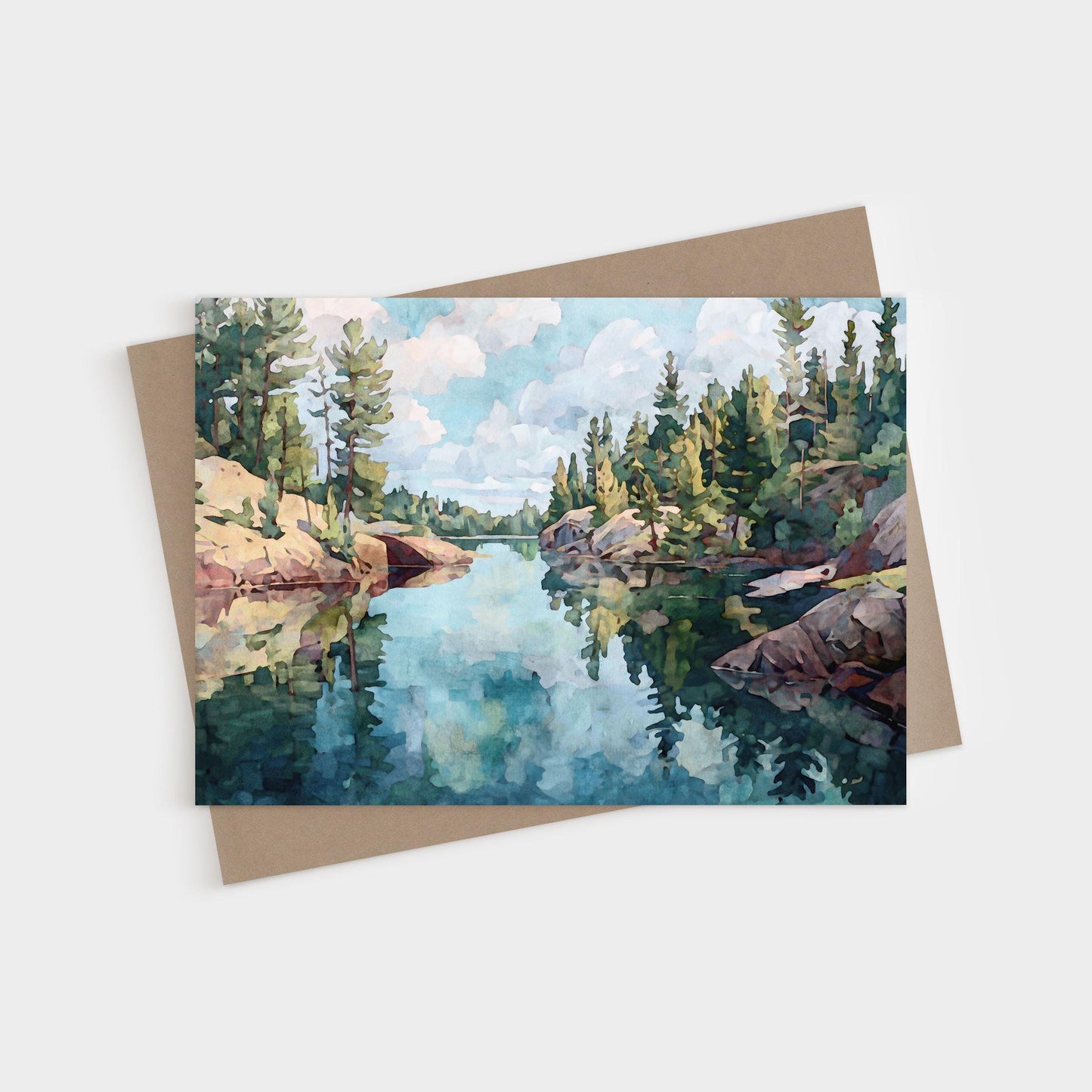 Horizontal greeting card featuring a watercolor-style painting of a calm northern lake, surrounded by rocky shores and evergreen pine trees, with reflections of the sky and clouds mirrored in the clear water.