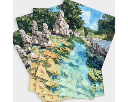 Set of greeting cards featuring a watercolor-style painting of a turquoise river with golden rocks beneath the water, framed by rocky white banks and lush green trees under a bright blue sky. Cards are fanned out in a layered display.