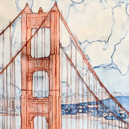 Close up of a watercolor greeting card featuring the Golden Gate Bridge in warm rust tones, stretching across a soft blue bay. The sky is filled with swirling, cloud-like linework, and subtle shoreline details appear in the distance. The foreground includes deep blue foliage, creating contrast with the pale background.
