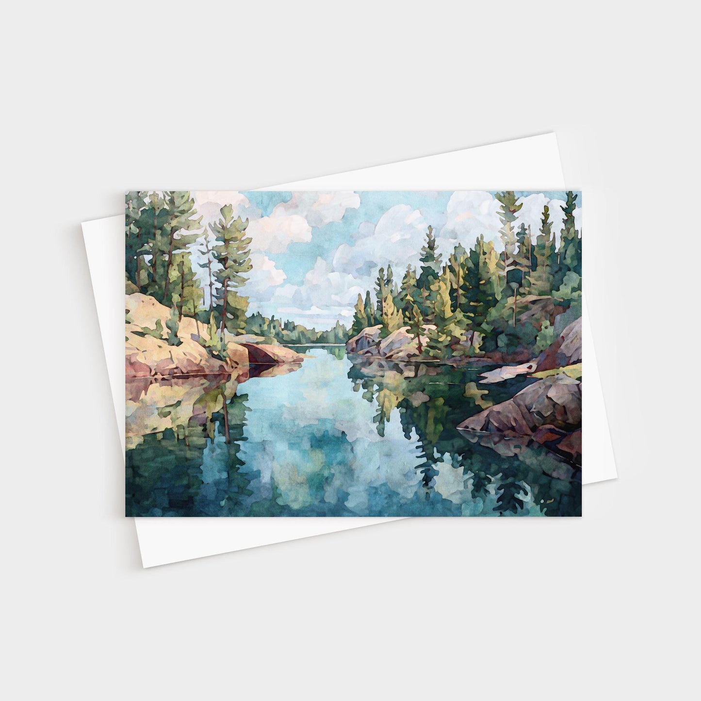 Horizontal greeting card featuring a watercolor-style painting of a calm northern lake, surrounded by rocky shores and evergreen pine trees, with reflections of the sky and clouds mirrored in the clear water.