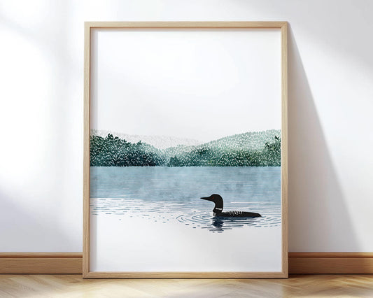 Minimalist watercolor illustration of a solitary common loon gliding across a calm blue lake. Framed in natural wood, leaning against a white wall.