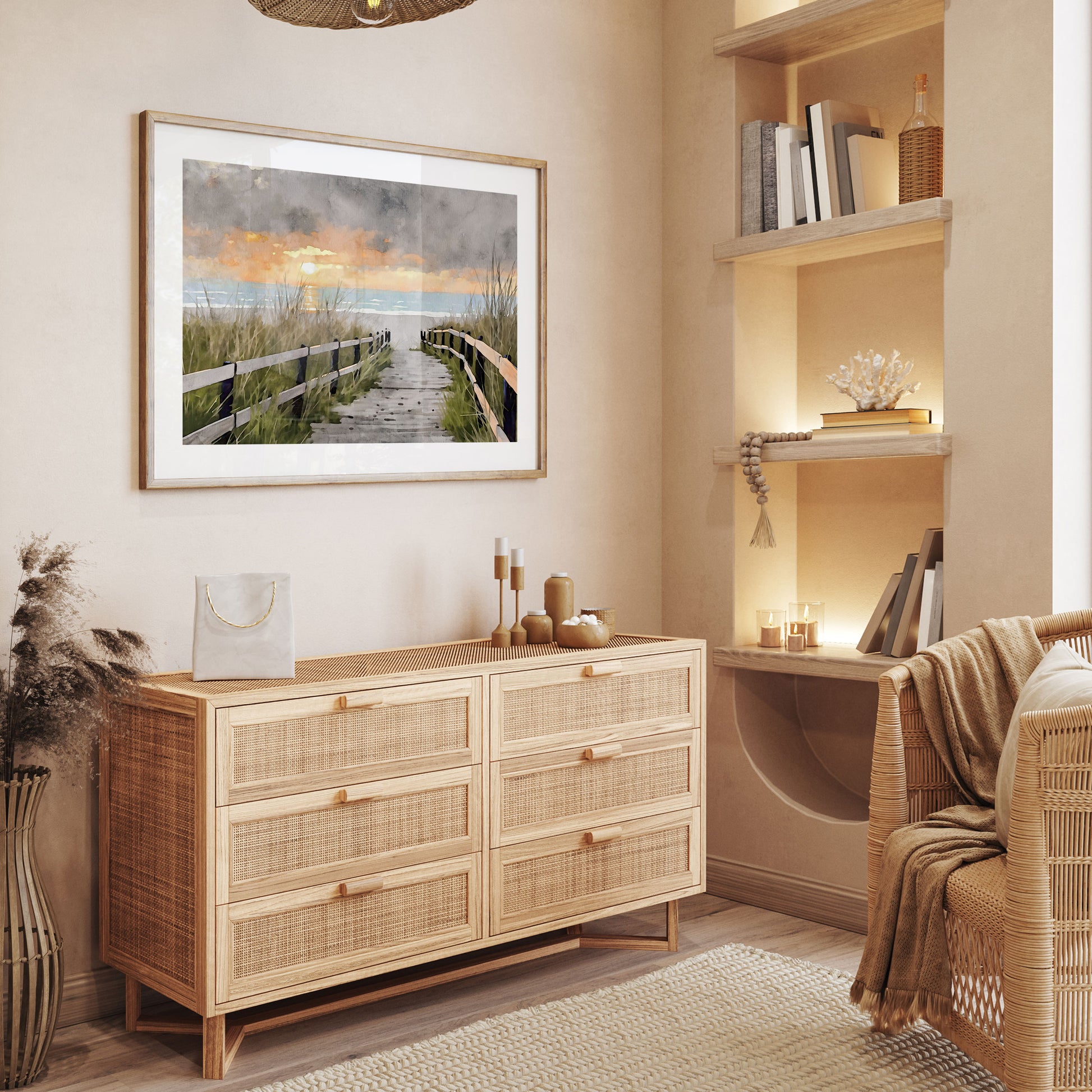 Framed artwork displayed in a cozy, neutral-toned room, featuring a watercolor-style depiction of a wooden boardwalk leading to the ocean at sunset. The artwork is mounted above a natural wooden dresser, surrounded by minimalist decor.