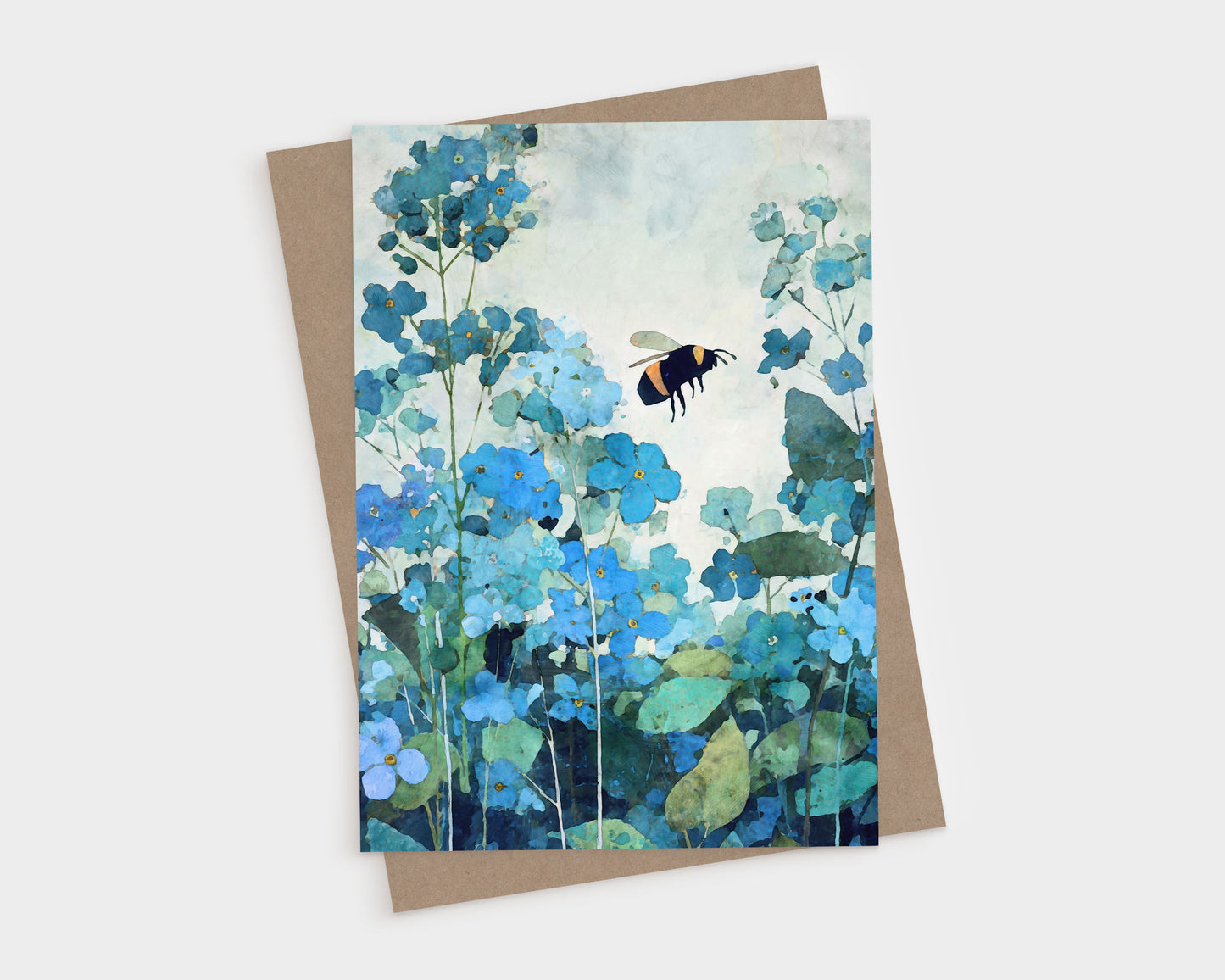 Watercolor-style greeting card featuring a bumblebee hovering among soft blue forget-me-not flowers with layered teal and green foliage. The card is shown with a kraft paper envelope, highlighting a calm, nature-inspired botanical design in cool blue tones.