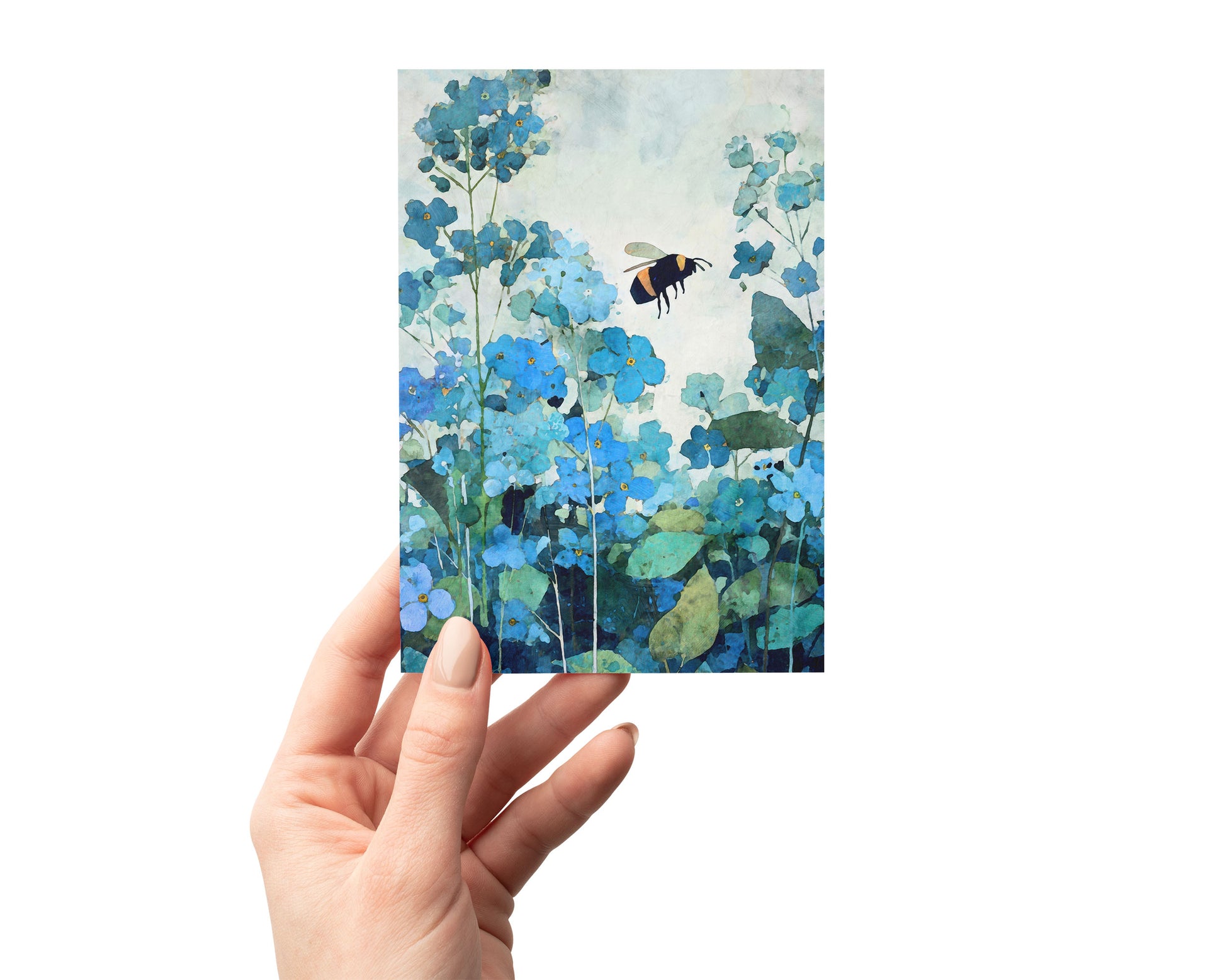 Hand holding a watercolor-style greeting card featuring a bumblebee hovering among blue forget-me-not flowers with layered teal and green foliage, set against a clean, light background.