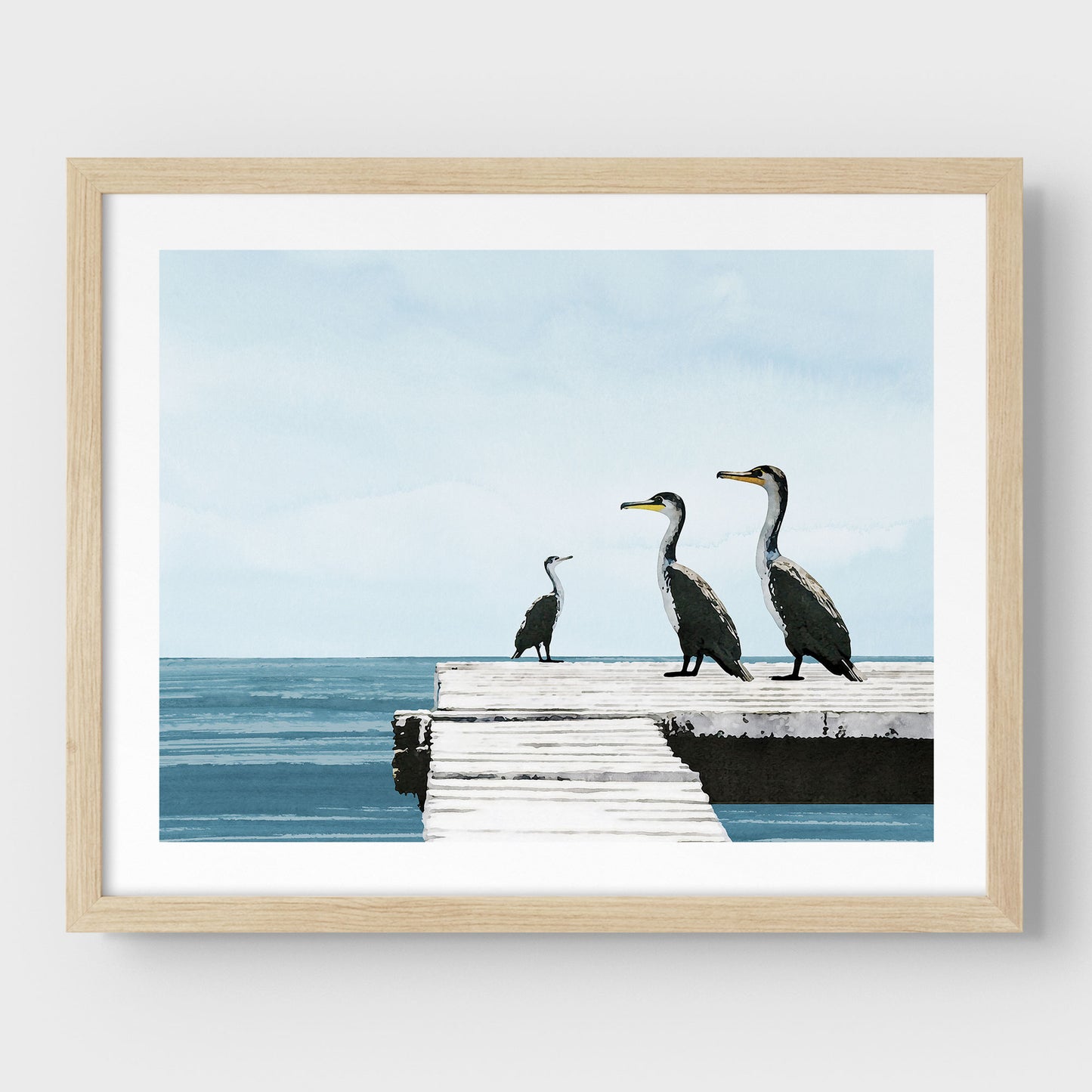 Natural wood framed illustration of three cormorants standing on a white wooden dock over a calm blue ocean under a pale sky, with minimalist styling and clean lines against a white background.