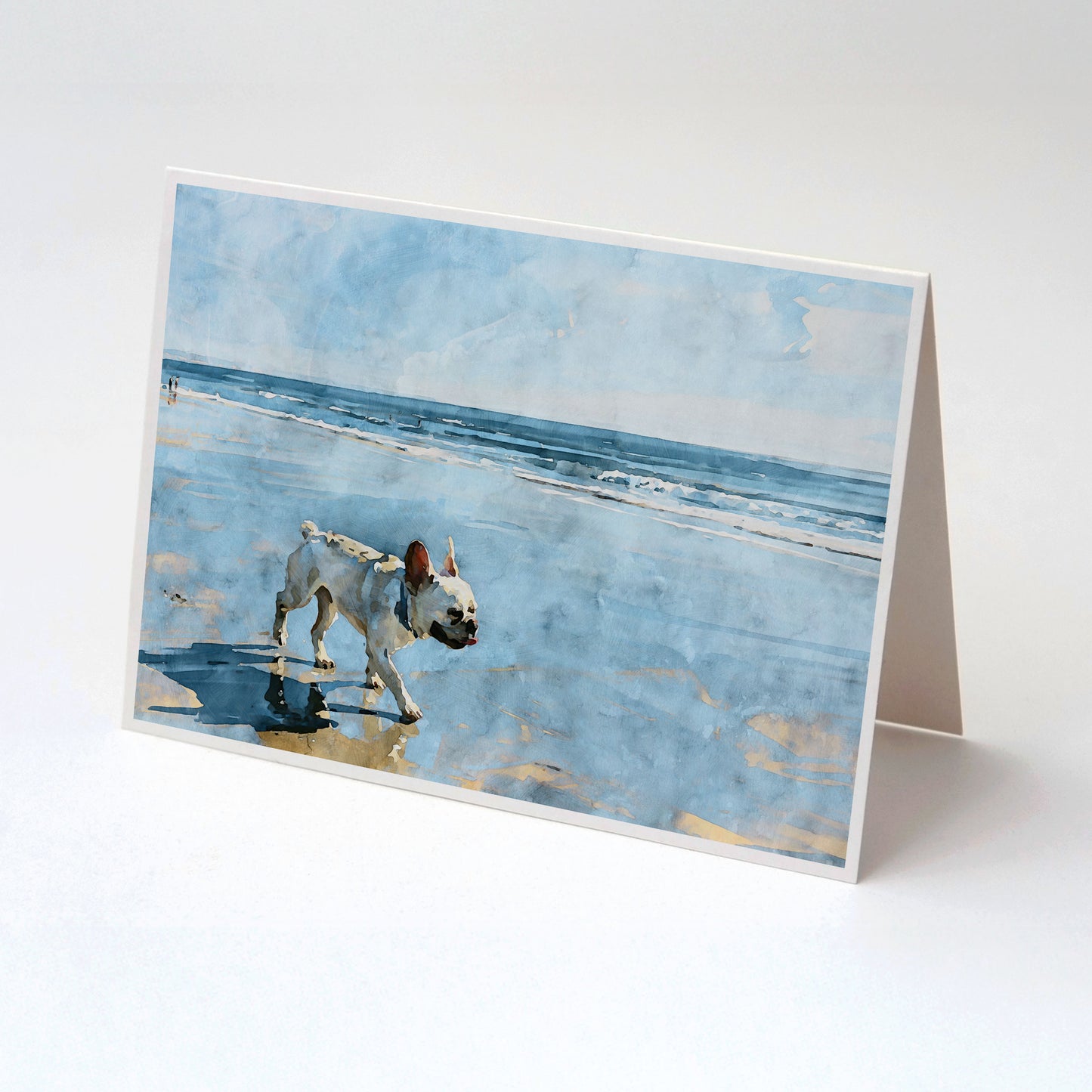 Tented folded note card with a cream French Bulldog beach watercolor and soft blue shoreline background.