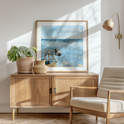 Square framed watercolor print of a cream French Bulldog on a beach shown in a styled interior.
