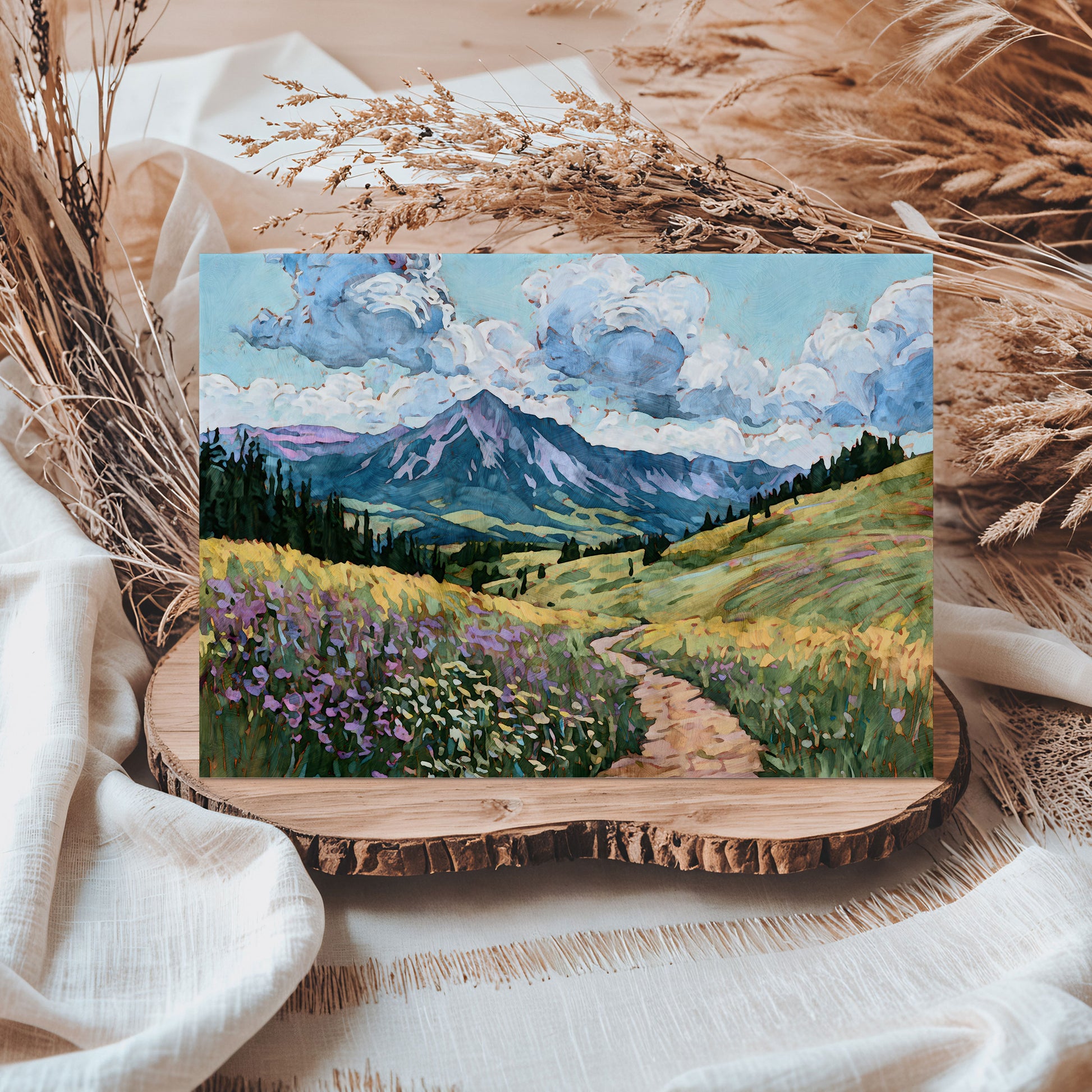 Painting of a mountain landscape with a path and flowers on a wooden coaster.