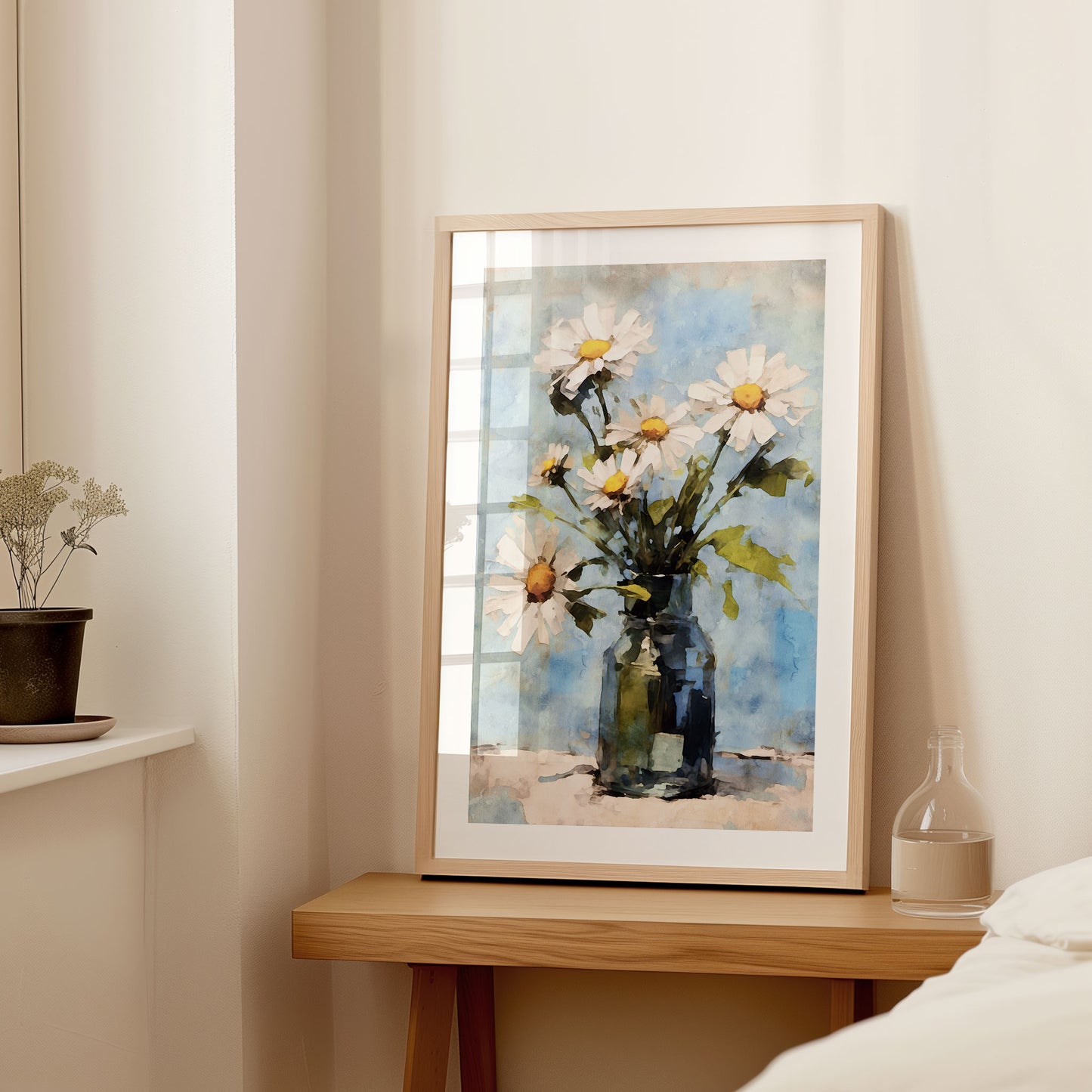Interior setting with a large framed watercolor painting of white daisies in a blue vase, displayed on a wooden console table next to a small vase and dried flowers.