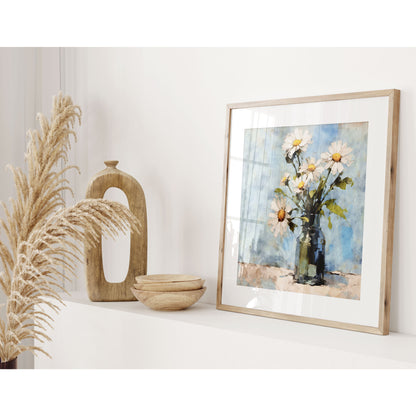 Square framed watercolor painting of white daisies in a blue vase on a shelf, accompanied by decorative wooden objects and dried grasses in a light-filled room.