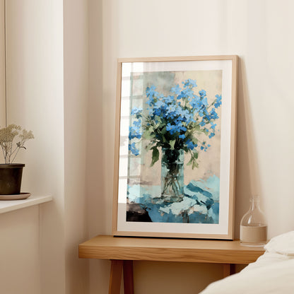 Interior setting with a large framed watercolor painting of vibrant blue forget-me-nots in a clear glass vase, displayed on a wooden console table next to a small vase and dried flowers.