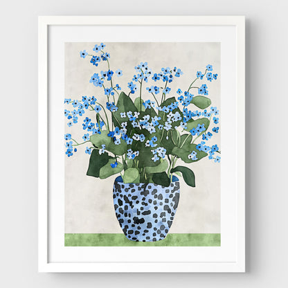 Artwork with a white frame and white border, featuring a watercolor-style depiction of blue forget-me-not flowers in a patterned blue vase, set against a soft neutral background and a green surface.