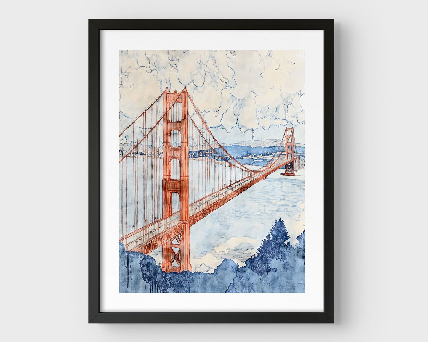 Watercolor-style painting of the Golden Gate Bridge, viewed at an angle with one tower in the foreground and the second in the distance. The bridge is rendered in soft rust red tones, stretching across a pale blue bay with hills and buildings in the background, and a cloudy sky above. Framed in black with a white border.