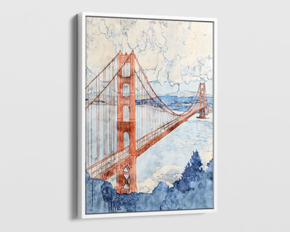 White framed canvas print of a watercolor-style Golden Gate Bridge painting, shown at a dramatic angle. The warm red-orange towers and cables contrast with a pale blue bay, cloudy sky, and deep navy trees in the foreground. The sleek black frame adds a modern touch to the soft, painterly design.