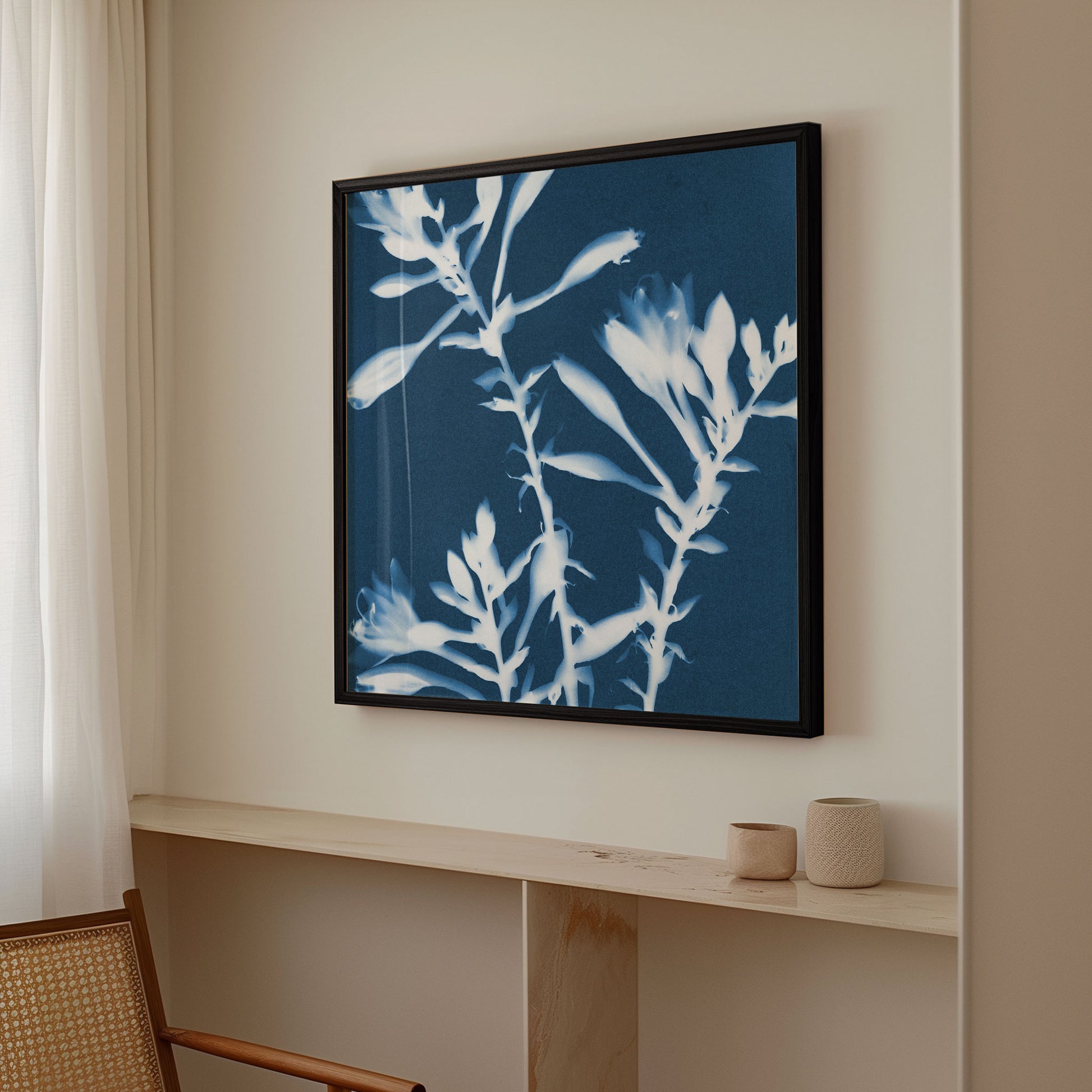 Framed cyanotype botanical print featuring white hosta flowers against a deep blue background, hanging on a neutral-colored wall above a marble shelf with ceramic decor.