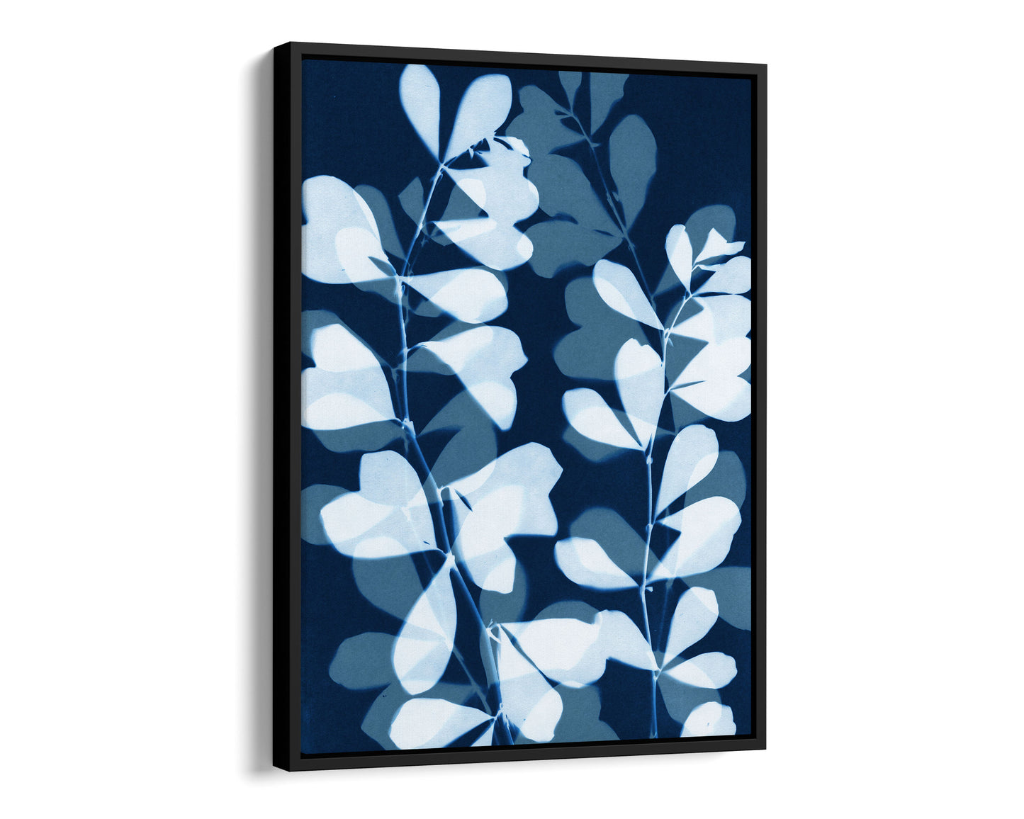 Black framed canvas print featuring overlapping cyanotype-style botanical leaves in soft blue and white against a deep navy background, creating a layered, translucent effect.