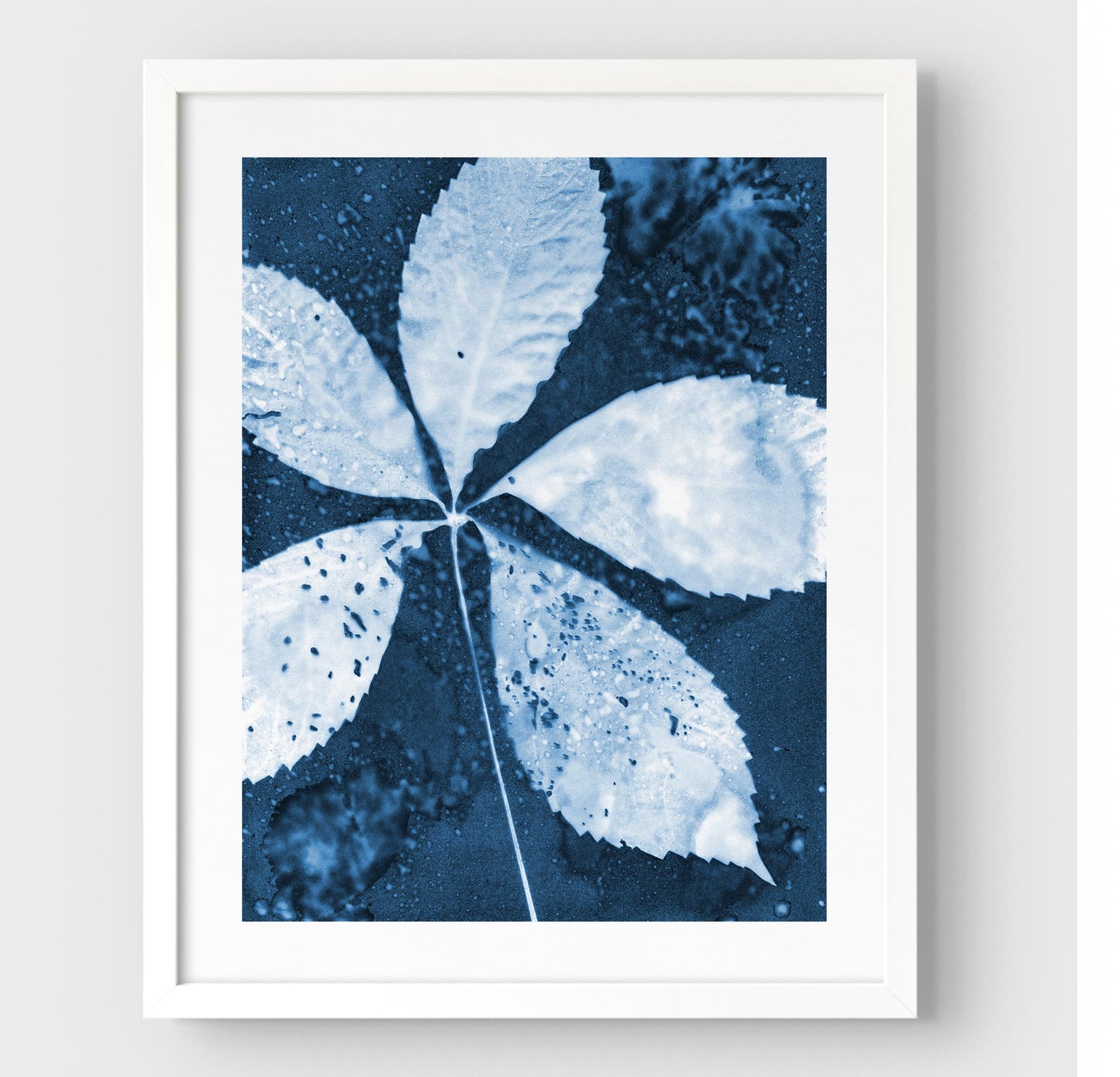 White framed cyanotype print featuring a detailed five-leaf botanical composition in deep blue and white, highlighting organic textures and natural patterns.