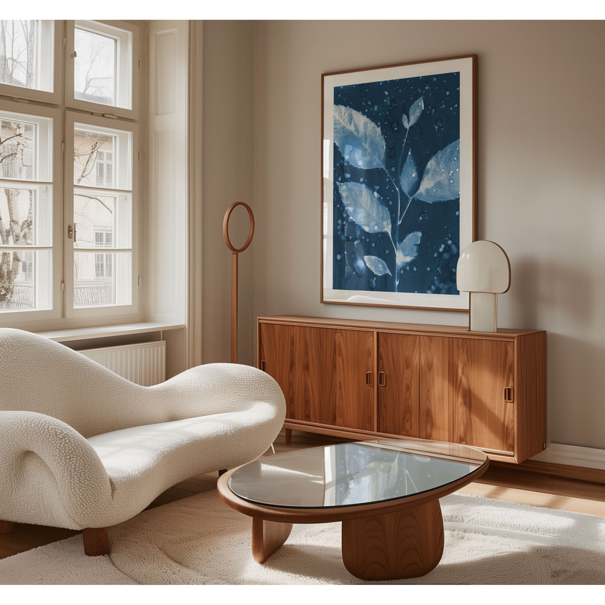 Framed cyanotype print of a leafy branch with water droplet textures, displayed in a modern living room with wooden furniture and neutral tones.