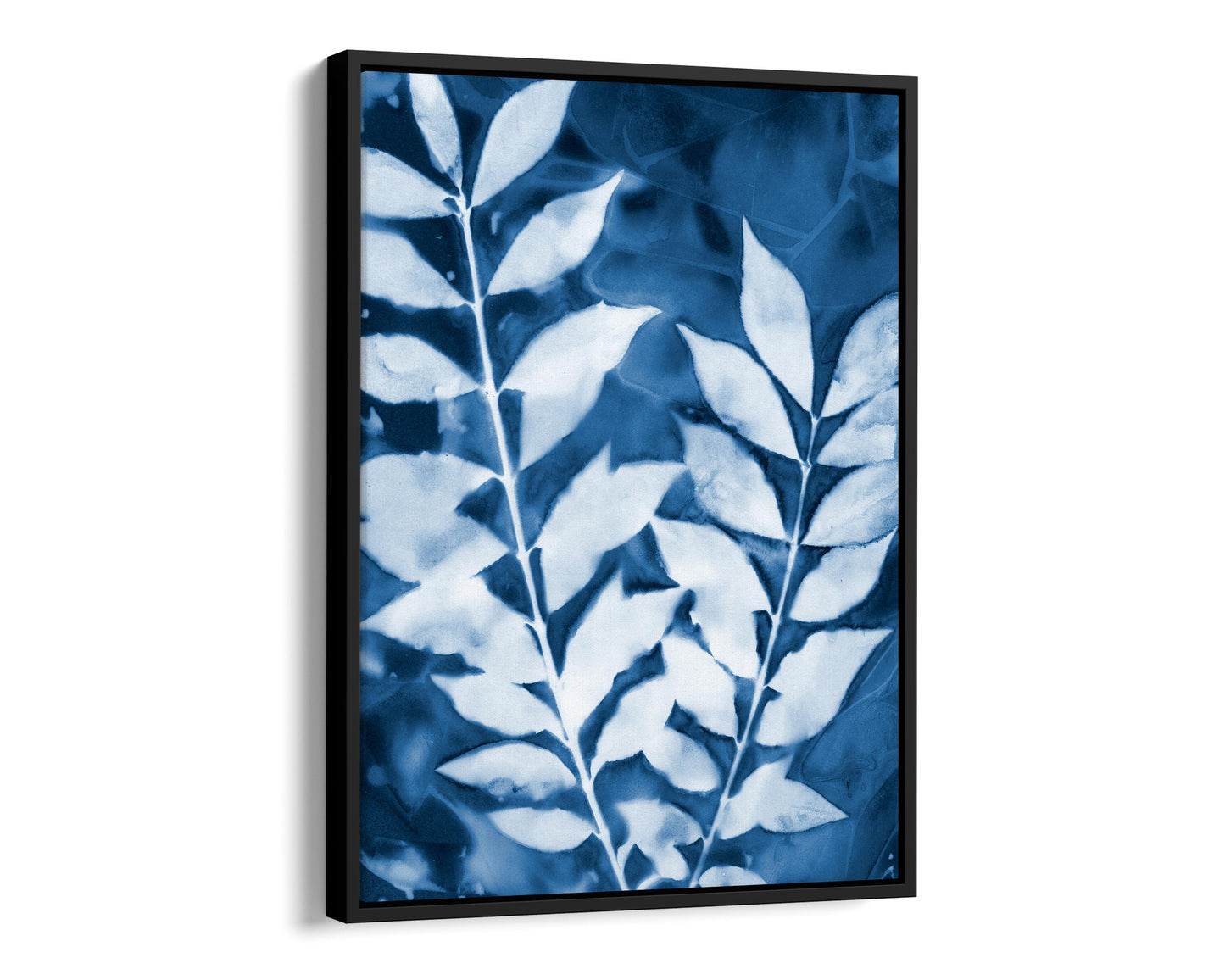 Black framed cyanotype print of two leafy branches in deep blue and white, highlighting organic textures and intricate vein details.