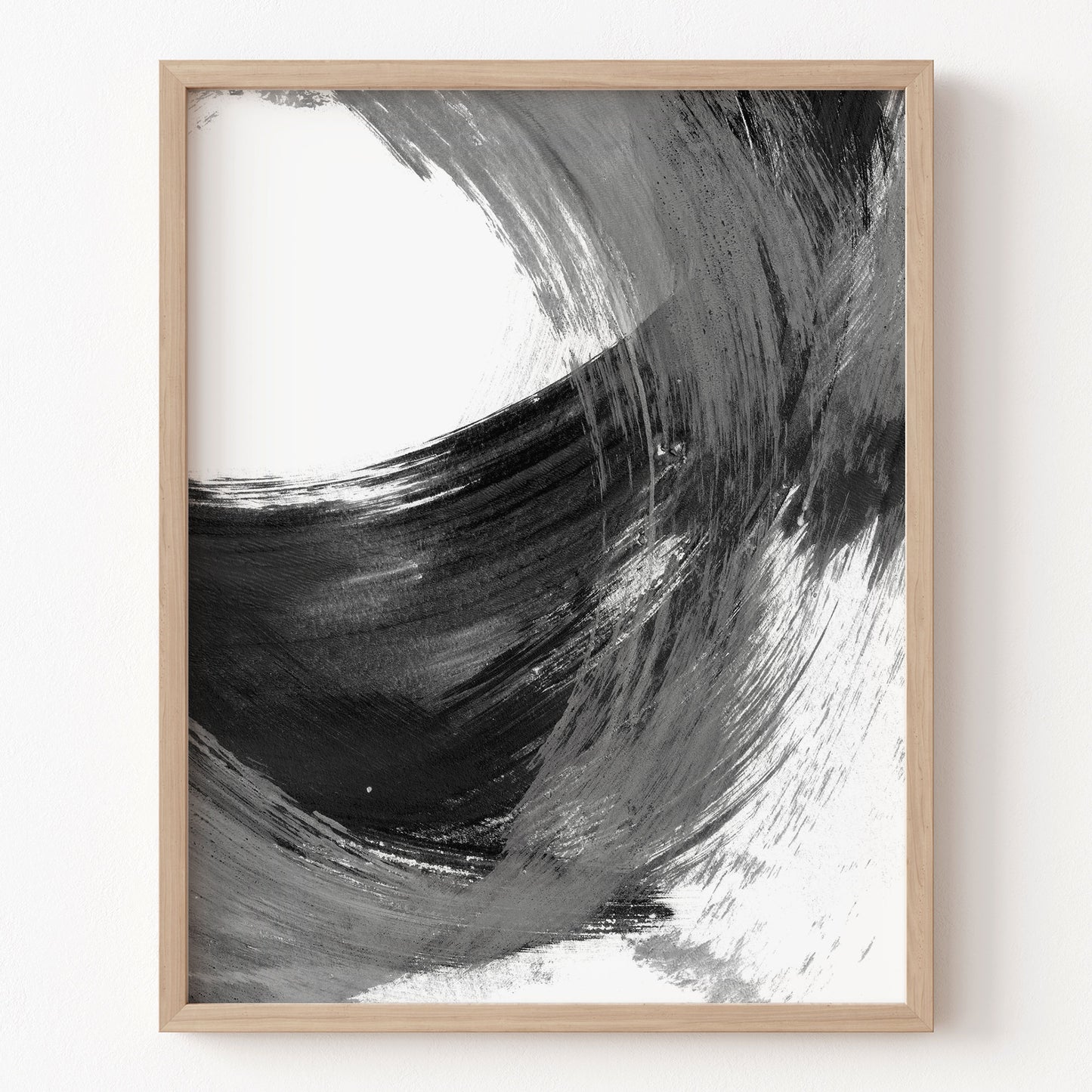 Framed abstract art print with black and white brush strokes on a white wall.