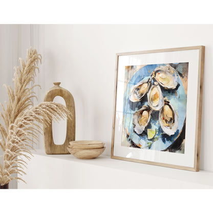 Framed square format watercolor painting of five oysters with lime slices on a blue plate on a shelf, accompanied by decorative wooden objects and dried grasses in a light-filled room.