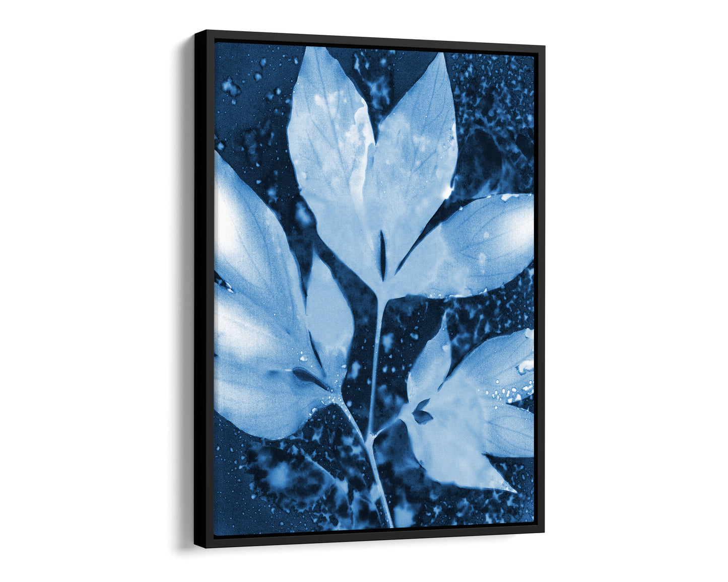 Black framed canvas of a cyanotype-inspired peony leaf cluster, rendered in soft pale blue against a rich indigo background with organic speckled textures and fluid, cloud-like shapes.