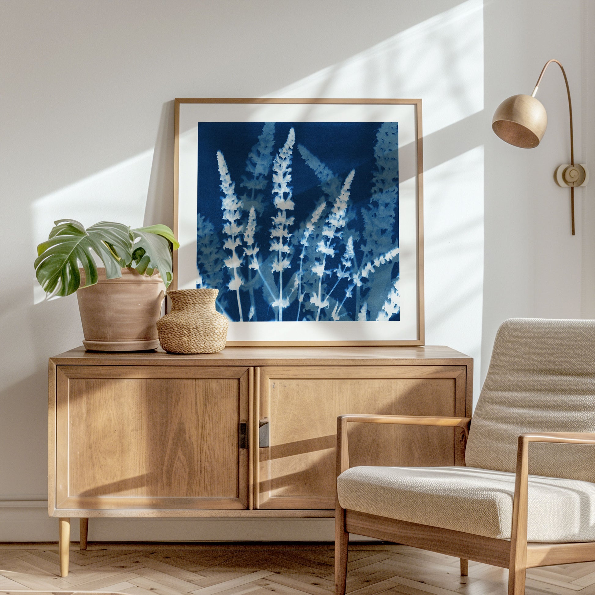Framed cyanotype print of blooming salvia stems displayed on a mid-century modern sideboard, surrounded by natural wood, soft sunlight, and minimalist decor in a bright, serene room.