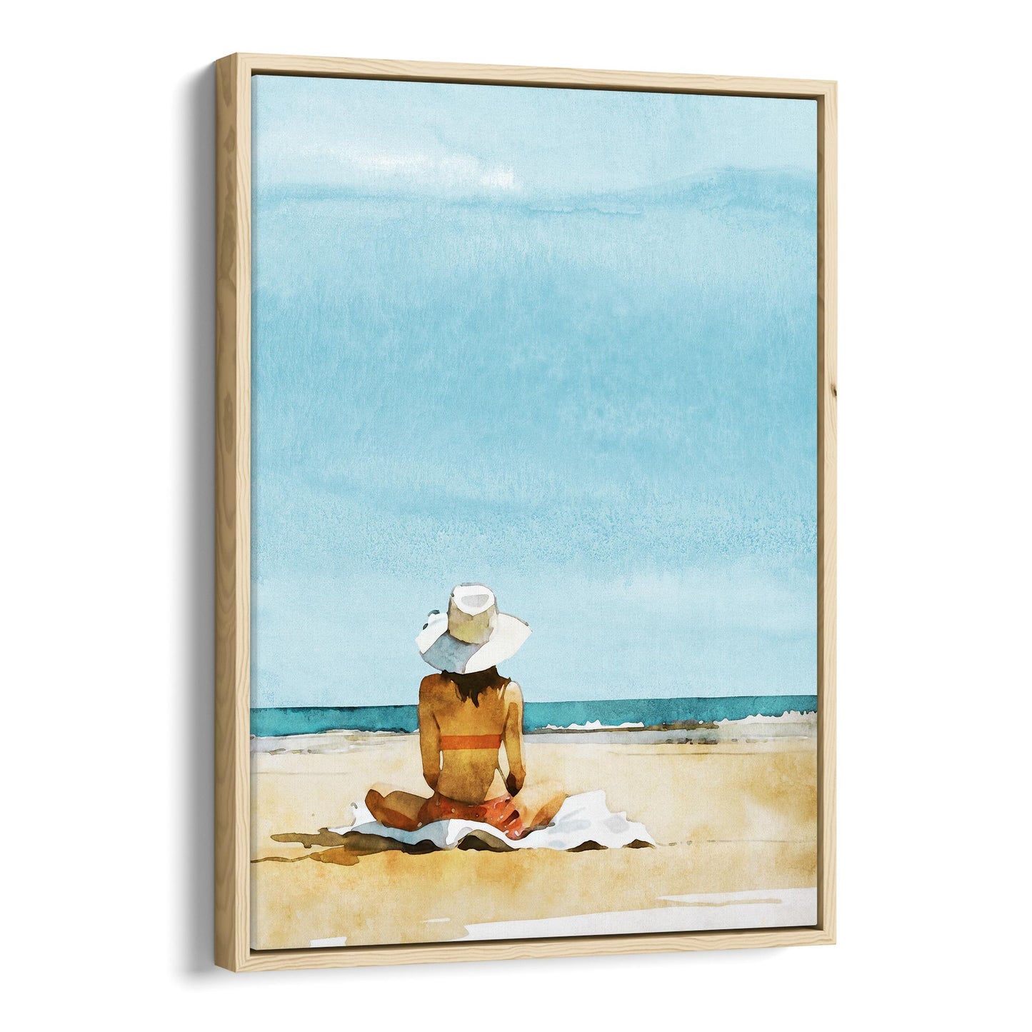 Natural wood framed canvas print featuring a person sitting on a towel at a beach, wearing a wide-brimmed hat and a swimsuit, with a clear blue sky and ocean.