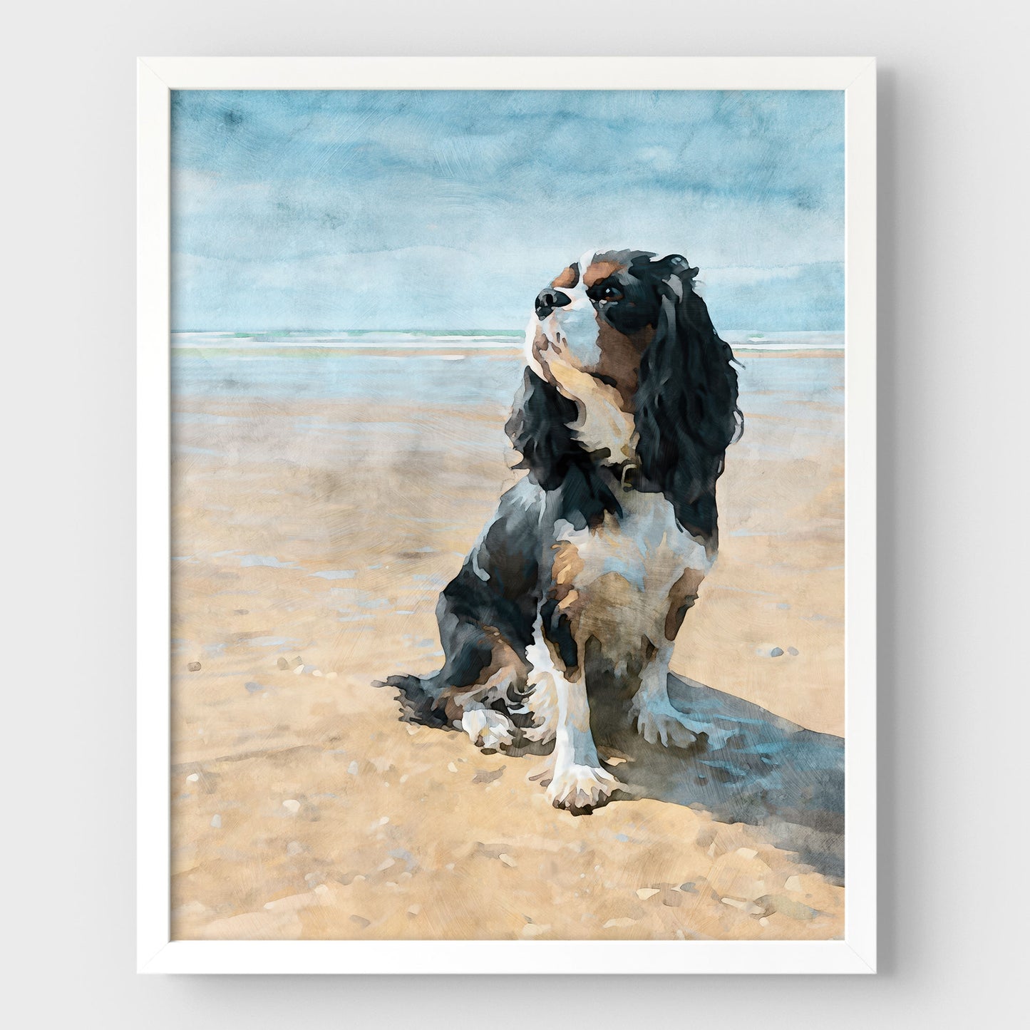 White framed artwork of a tricolor King Charles spaniel on a beach